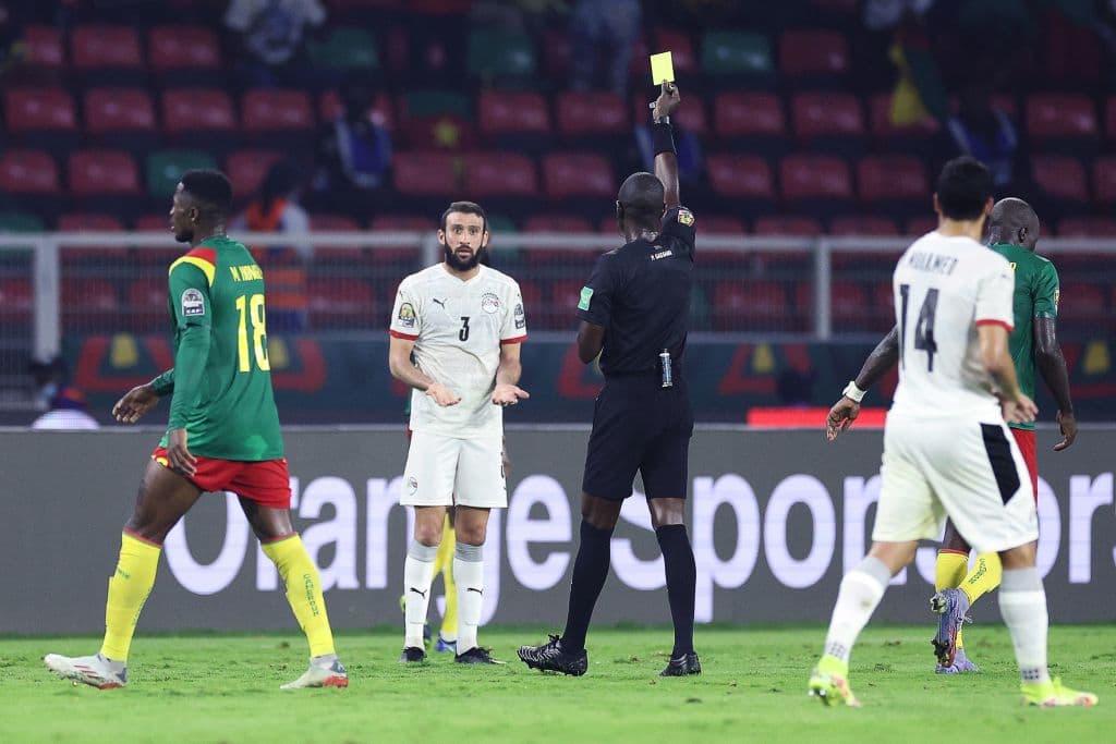 A referee gives a yellow card during an international fixture