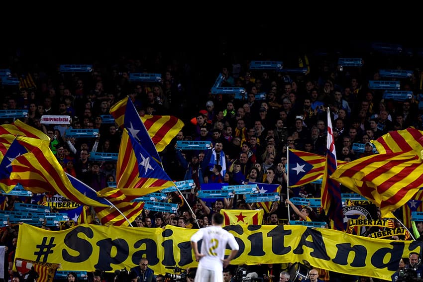 A real madrid player watches on as barcelona supporters put on a political display